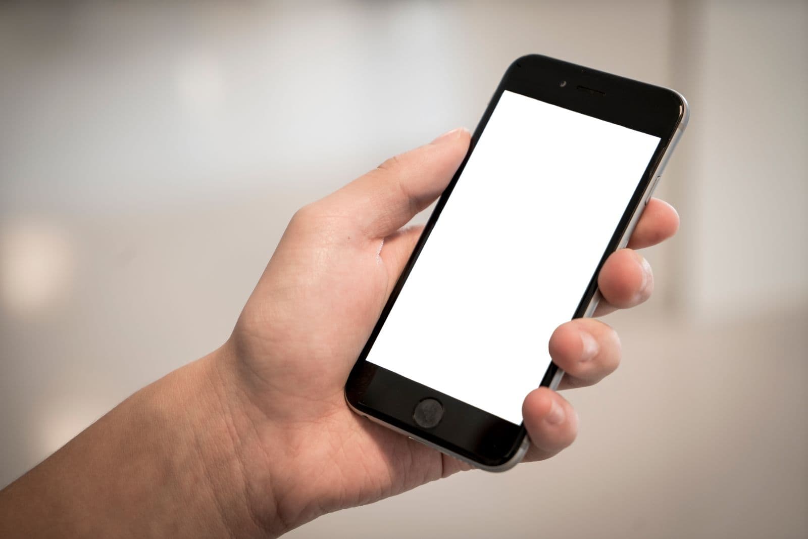 Persona sosteniendo un teléfono móvil con la pantalla en blanco, representando la versión móvil de una página web