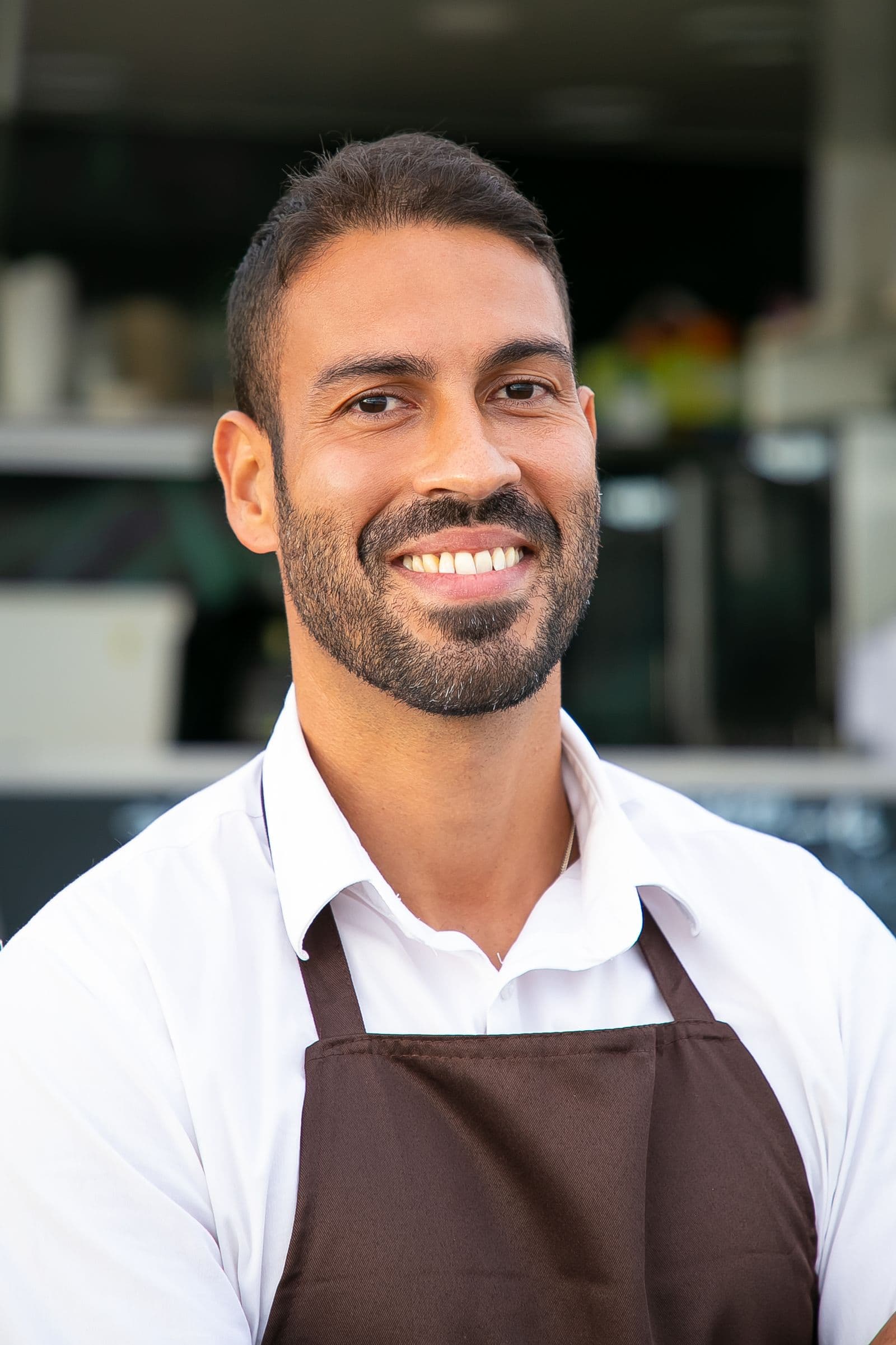 Dueño de un negocio local sonriendo frente a su establecimiento